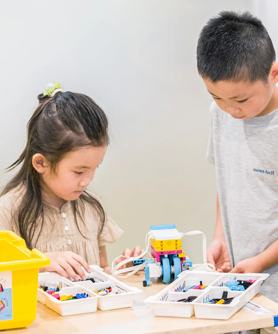 パーツを手に取り、ロボットを組み立てる子どもたち