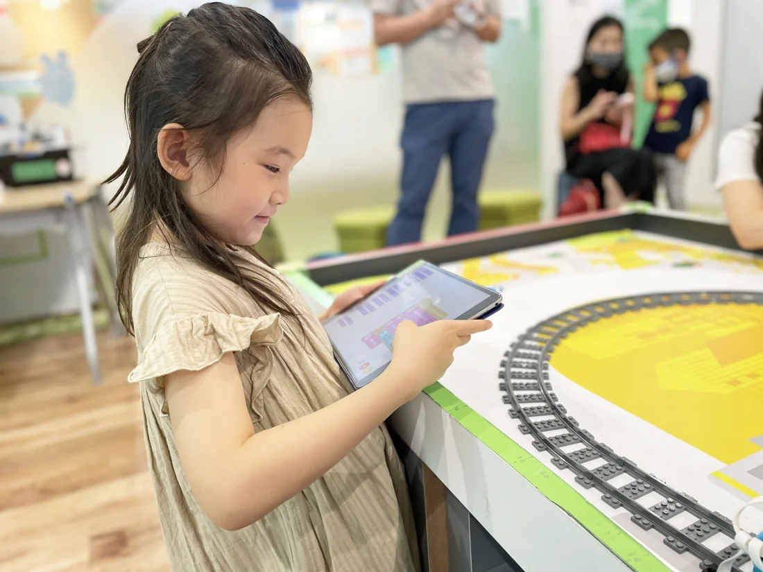線路のそばでタブレットを操作する子ども